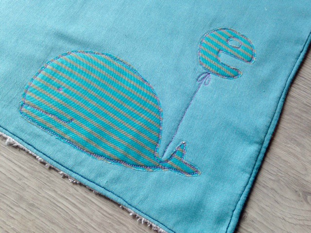 Asciugamano personalizzato per il fasciatoio con il monogramma del bambino appeso ad una dolce e morbida balena